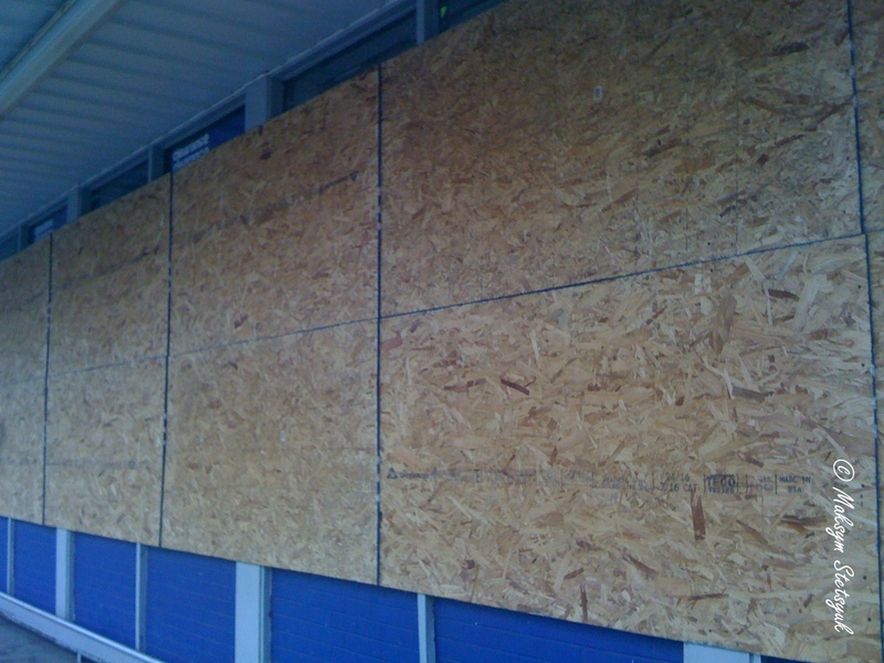 Вікна сусіднього магазину забиті фанерою.